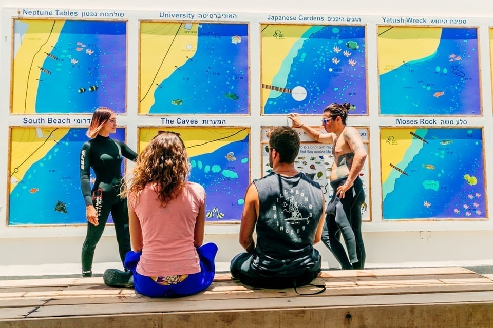four divers looking at dive site maps while being briefed
